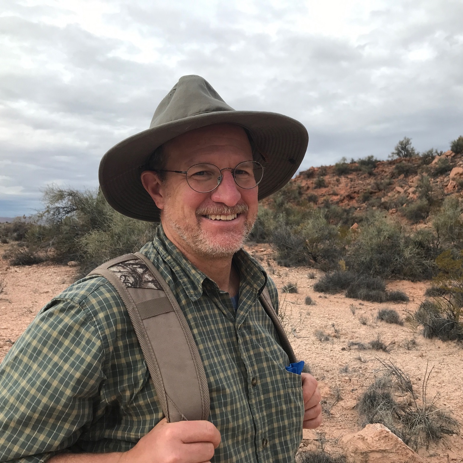 Portrait of man with plants and rocks in background.